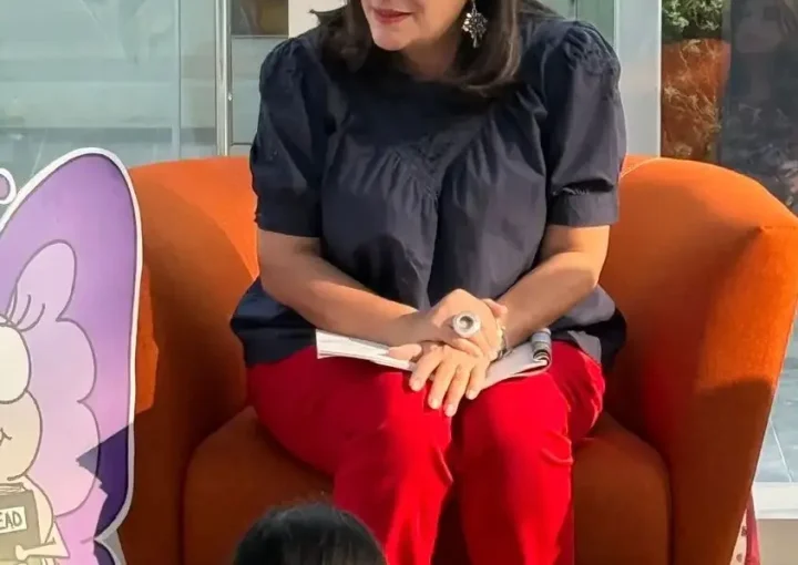 Mother-turned-author reading her children’s book to young kids at a community storytelling event, passing on a renewed love for stories and imagination