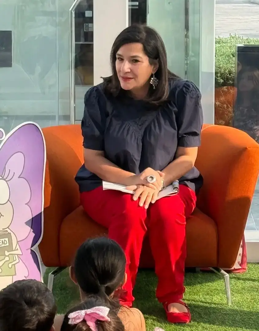 Mother-turned-author reading her children’s book to young kids at a community storytelling event, passing on a renewed love for stories and imagination