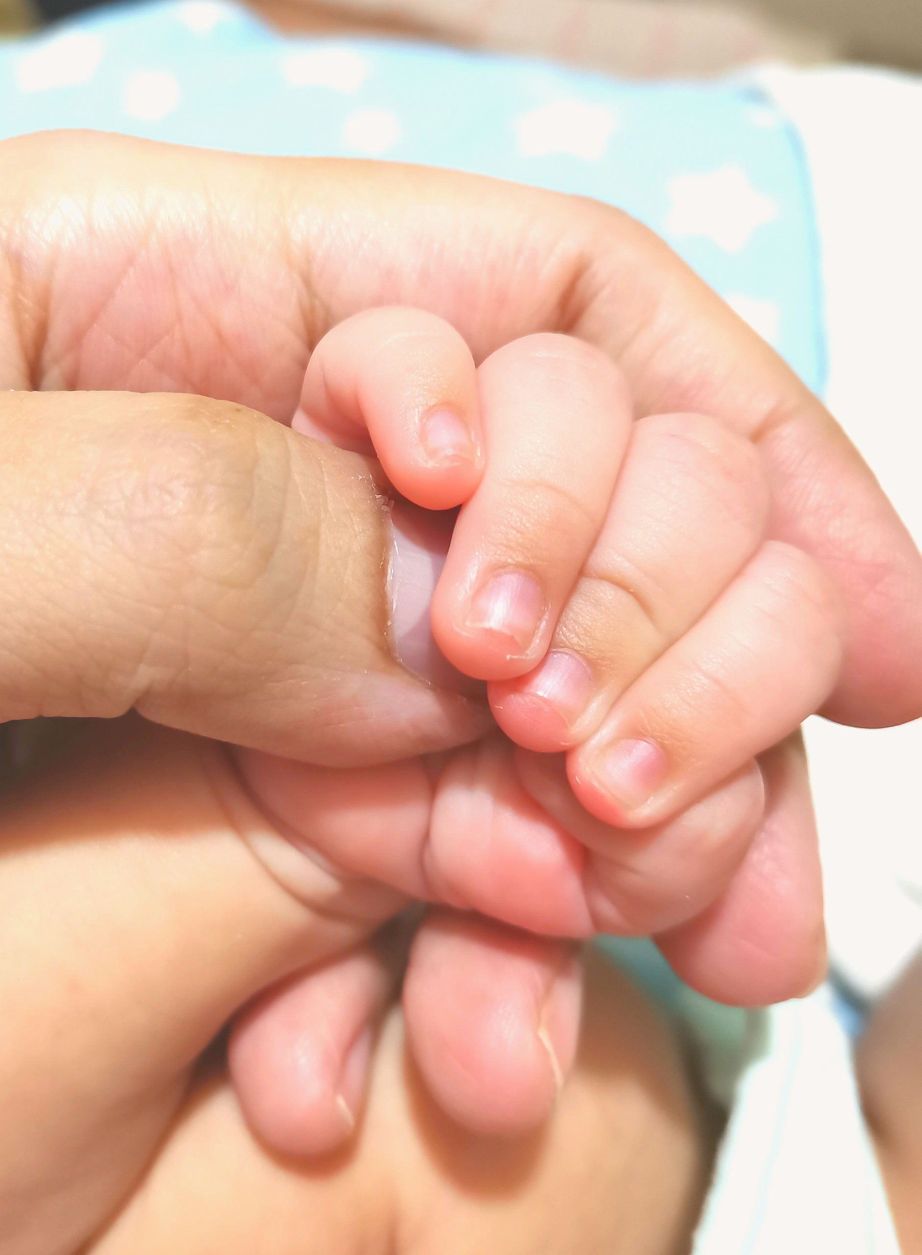 A mother holding the hand of her rainbow baby
